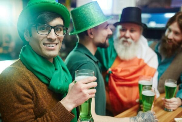 multicultural friends watching tv and clinking glasses, saint patrick day concept